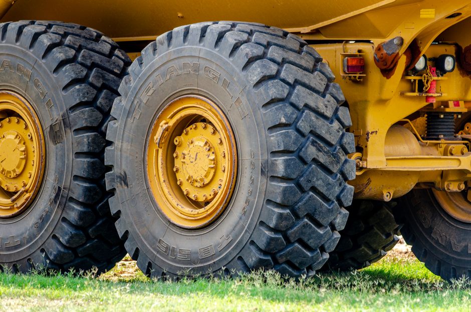 Close-up view of large industrial truck tires in an outdoor setting, showcasing heavy equipment and rugged design.